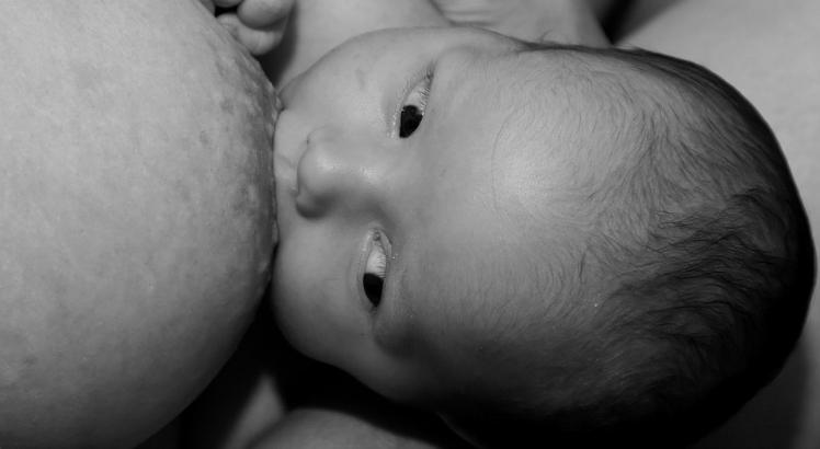 Imagem de um bebê sendo amamentado.